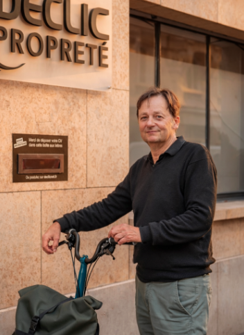 Guy Garcia, dirigeant de DECLIC Propreté, qui pose avec son vélo devant l'enseigne.